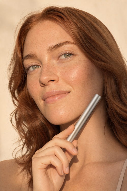 Woman with freckles holding the lash serum