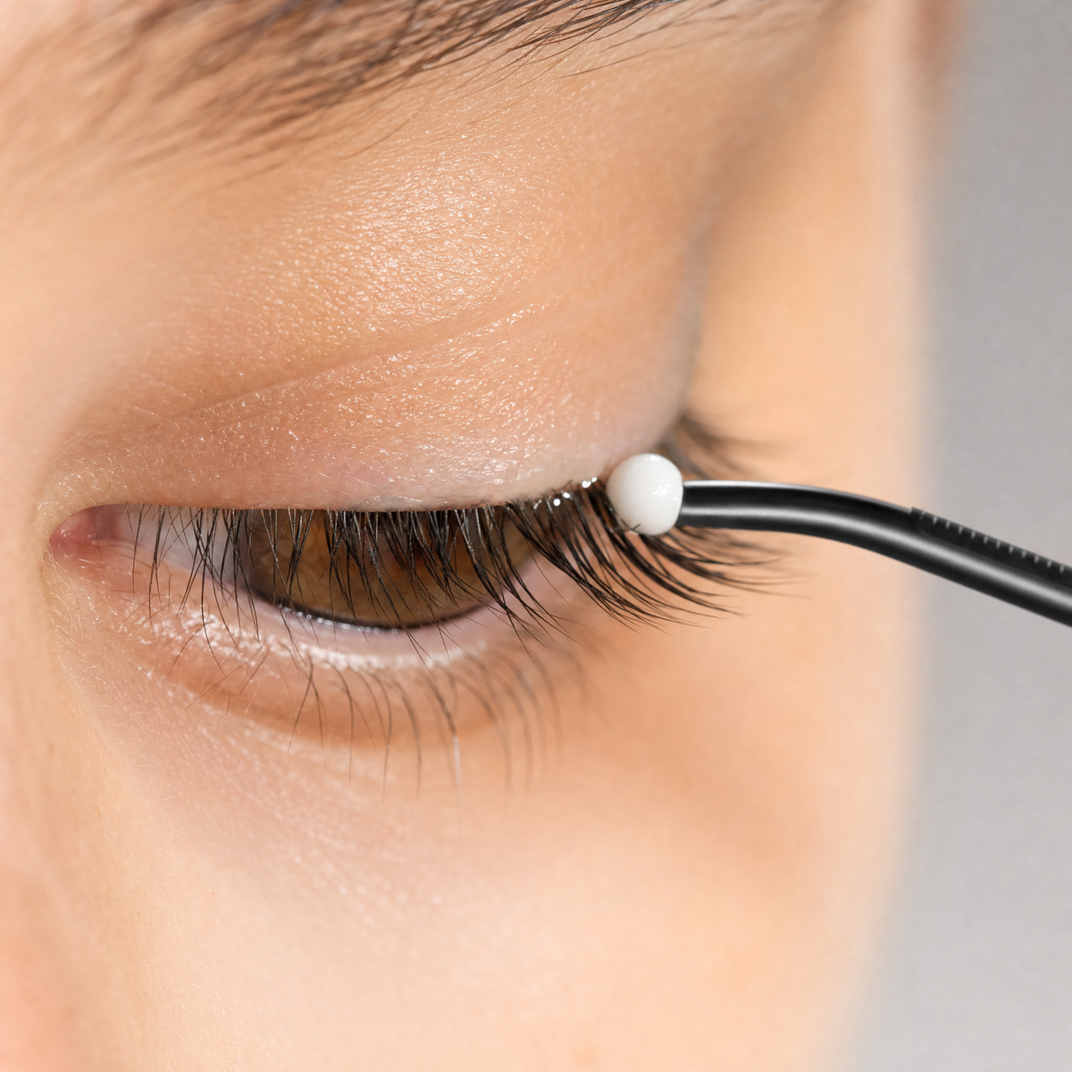Ball-tip applicator placing a small amount of serum at the lash roots
